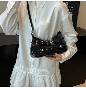 Détail du sac baguette noir brillant avec boucles argentées et œillets style biker
