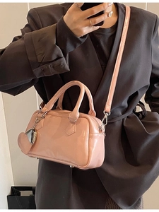 Pink patent leather Boston bowling bag with heart charm shown on model in crossbody style