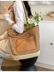 Straw woven tote bag with brown leather handles and decorative floral interior detail