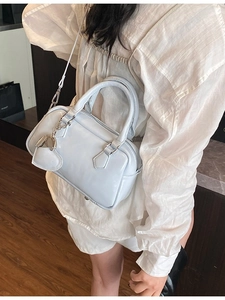 Light blue glossy bowling bag with heart charm shown on a female model for daily commute