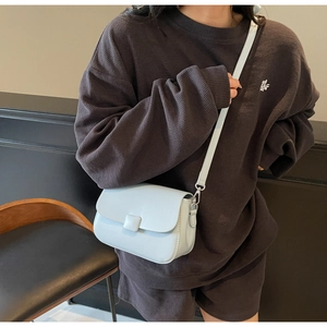 Close-up of light blue small square crossbody bag with square buckle on dark waffle outfit