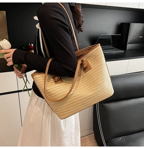 Détail d'un grand sac cabas en paille avec texture tressée et anses en cuir marron