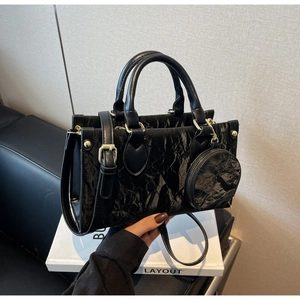 Détails de la texture du cuir plissé noir sur un sac cabas avec quincaillerie dorée élégante