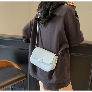 Crossbody view of light blue small square bag with flap design and premium leather texture