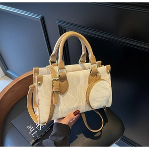 Détail d'un sac cabas crème avec finitions en cuir marron et une petite pochette ronde
