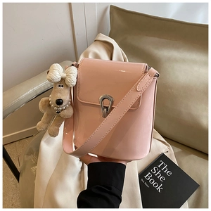 Détail du sac seau en cuir verni rose avec fermoir argenté et charm de nœud en peluche