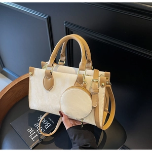Détail d'un cabas chic crème avec anses en cuir fauve et petit porte-monnaie rond
