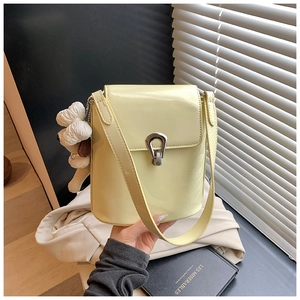Gros plan du sac seau en cuir verni crème avec fermoir argenté et charm chien peluche