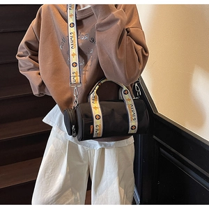 Détail du sac bandoulière cylindrique en toile noire avec sangle jacquard et porte-monnaie