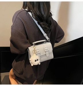 Light blue faux leather satchel with dual buckles and a white plush monster pendant detail
