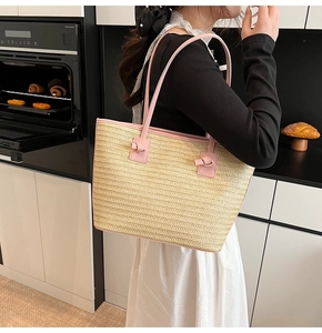 Détail du sac cabas en paille tissée avec bordure rose pâle et poignée à nœud sur un comptoir
