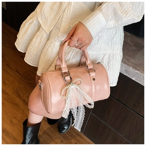 Detail of pink glossy leather Boston bag with pearl bow and white lace charms