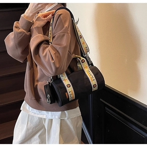 Détail du sac bandoulière cylindrique noir avec sangle jacquard et petit porte-monnaie