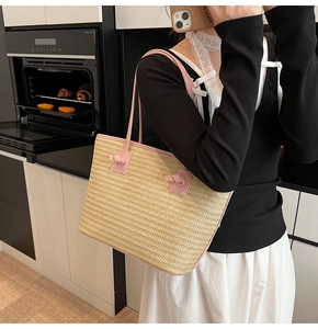 Détail d'un grand sac cabas en paille avec des anses en cuir rose et des surpiqûres