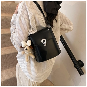 Détail du sac seau noir avec fermoir argenté et breloque peluche portée par le mannequin