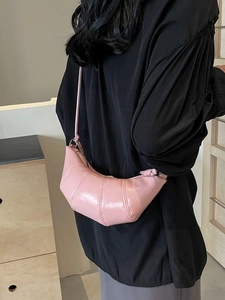 Pink croissant-style crossbody bag with quilted leather texture and knotted strap detail