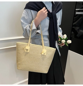 Détail d'un sac cabas en paille tressée avec nœud décoratif sur la bandoulière