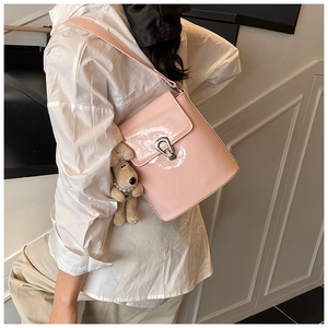Détail du sac seau en cuir verni rose avec fermoir argenté et breloque chien en peluche