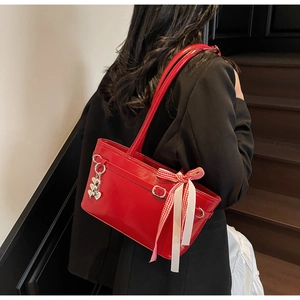 Détail du sac à épaule en cuir verni rouge avec anneaux argentés et breloque coeur