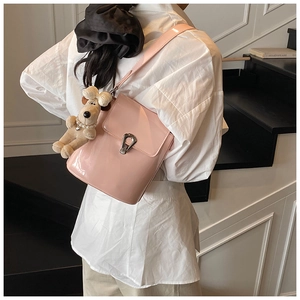 Détail du sac seau en cuir verni rose avec fermoir argenté et breloque chien en peluche