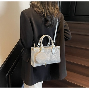 Détail du sac à main plissé argenté avec texture métallique et mini pochette ronde amovible