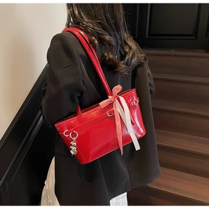 Détail du sac rouge brillant avec breloque cœur et nœud en ruban à carreaux rouge et blanc