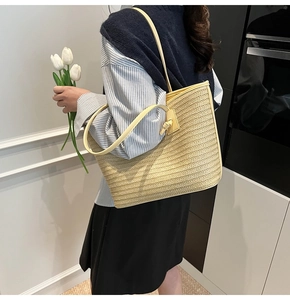 Détail d'un grand cabas en paille tressée beige avec bandoulière en cuir jaune pâle