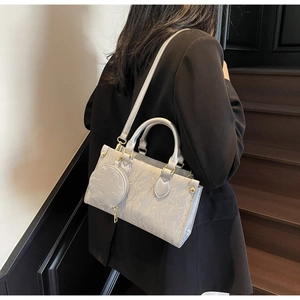Sac à main argenté plissé avec pochette ronde porté par un mannequin en costume
