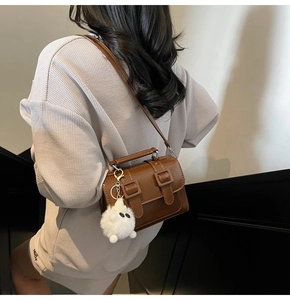 Deep brown retro crossbody bag with decorative double buckles and white ghost pendant charm