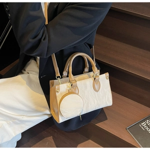Détail du sac à main beige texturé avec poignées en cuir marron et mini pochette ronde