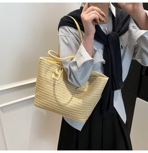 Détail du sac cabas en paille montrant la texture tissée et les anses en cuir
