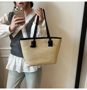 Détail de la texture en paille et de l'anse en cuir noir sur le grand sac cabas d'été
