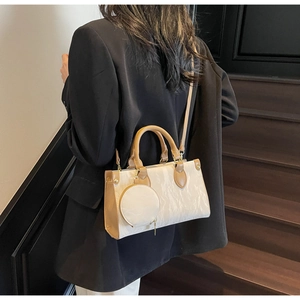 Détail d'un sac bandoulière beige et kaki avec petit porte-monnaie sur un mannequin