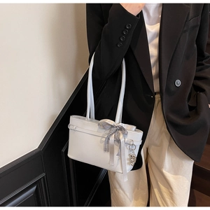 Détail du sac bandoulière bleu clair avec ruban nœud et breloque ours en métal
