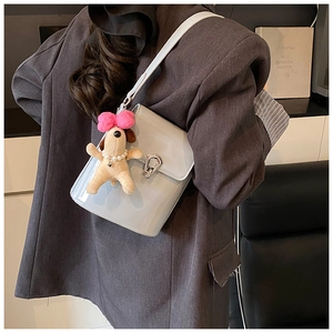 Détail d'un sac seau en cuir gris clair avec fermoir argenté et pendentif chien