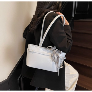 Détail d'un sac à bandoulière bleu clair avec breloque cœur et nœud à carreaux noir et blanc