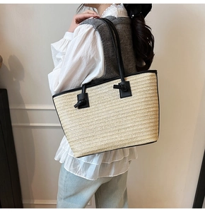 Détail du sac cabas en paille tissée avec anses en cuir noir et nœuds décoratifs