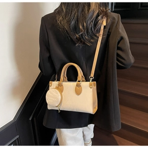 Détail du sac à main crème avec lanières marron et petit porte-monnaie rond suspendu