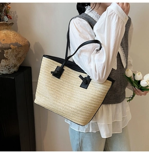 Détail du cabas en paille tissée avec poignées en cuir noir et design à nœuds élégant