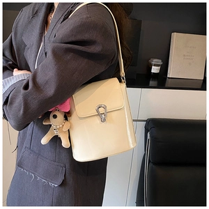 Détail du sac seau en cuir verni crème avec fermoir argenté et breloque chien
