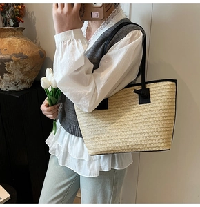 Détail du sac cabas d'été en paille avec anses en cuir noir et texture tissée