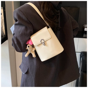 Détail du sac seau en cuir verni crème avec fermoir argenté et charm chiot peluche