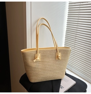 Gros plan du sac cabas en paille tressée beige avec texture détaillée et bandoulière nouée