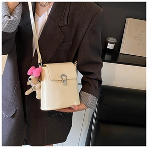 Détail du sac bandoulière beige brillant avec fermoir en U et charme de chiot mignon