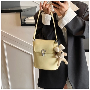 Détail d'un sac seau jaune verni avec fermoir argenté et breloque chien peluche