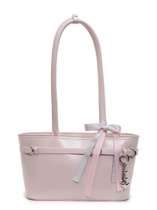 Sac à bandoulière en cuir verni rose avec nœud et pendentifs cœur sur fond blanc