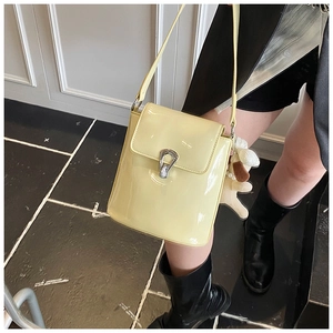 Gros plan du sac seau jaune clair avec boucle en U argentée et charme de chiot en peluche