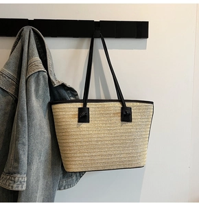 Détail du sac cabas en paille avec bordure et poignées en cuir noir en présentation