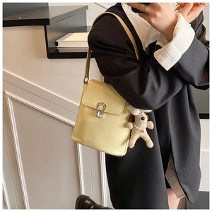 Détail du sac seau crème avec boucle argentée et charmant pendentif chiot peluche