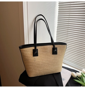 Détails des poignées en cuir noir nouées main sur un sac cabas en paille tissée